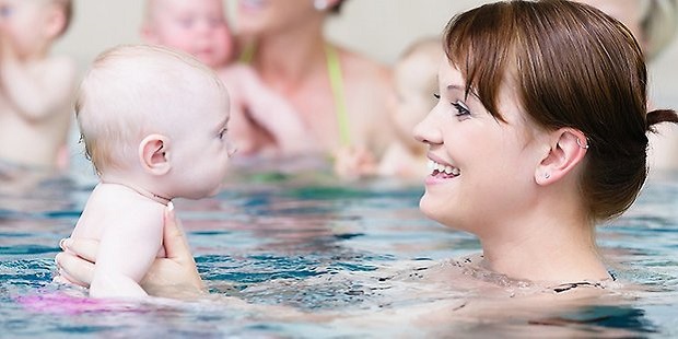 Bilden visar en mamma och ett barn som badar tillsammans i en pool